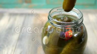 人的手指从木桌上的玻璃罐中取出<strong>腌黄瓜</strong>或<strong>腌黄瓜</strong>。